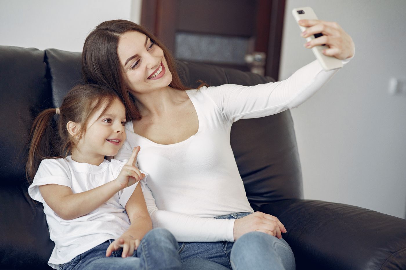A mother and daughter smiling while taking a photo with a phone
